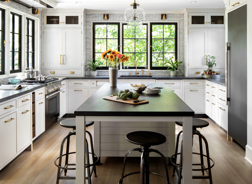 Inspiration for a mid-sized country u-shaped separate kitchen in New York with an undermount sink, shaker cabinets, granite benchtops, grey splashback, coloured appliances, light hardwood floors, with island, brown floor, white cabinets, matchstick tile splashback and black benchtop.