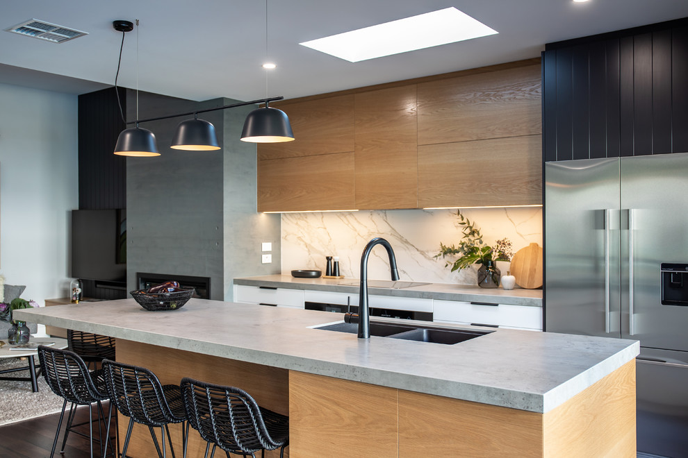 This is an example of a mid-sized contemporary galley kitchen pantry in Adelaide with a double-bowl sink, black cabinets, concrete benchtops, white splashback, stone slab splashback, black appliances, dark hardwood floors, with island, brown floor and grey benchtop.