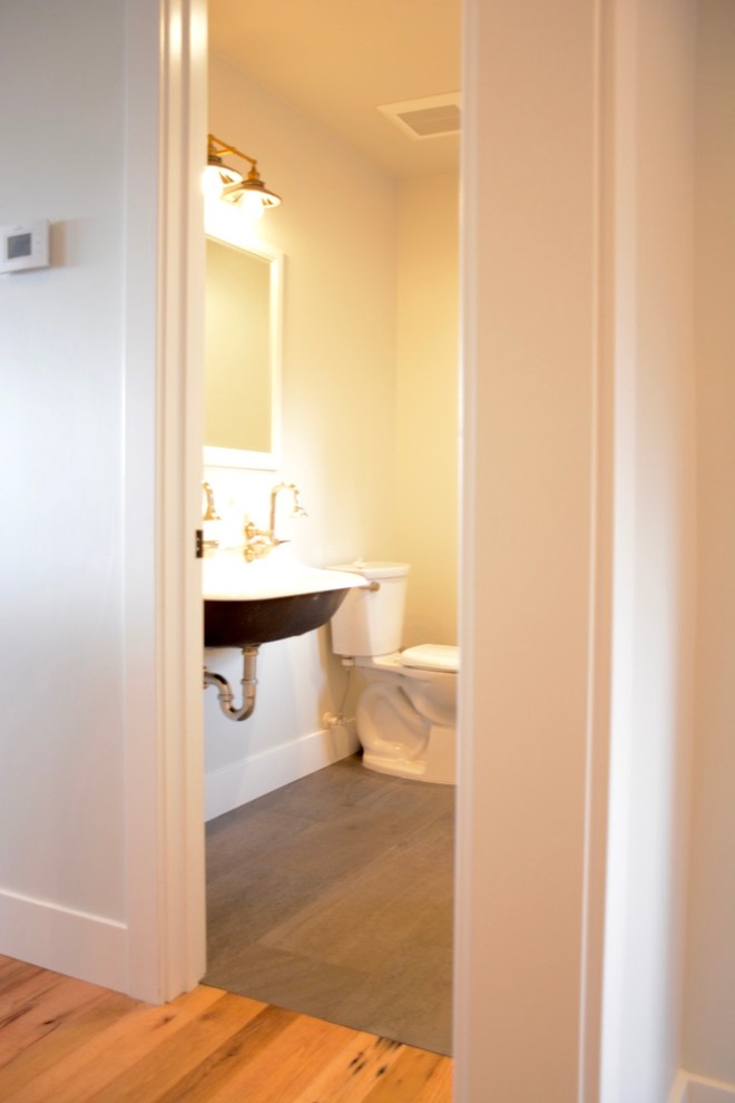 Small country 3/4 bathroom in Other with a two-piece toilet, white walls, light hardwood floors and a pedestal sink.