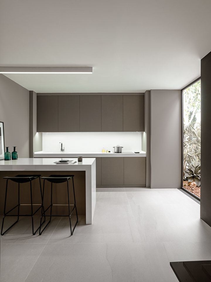 Inspiration for a mid-sized modern single-wall open plan kitchen in Other with an integrated sink, flat-panel cabinets, brown cabinets, white splashback, ceramic floors, beige floor, white benchtop and a peninsula.