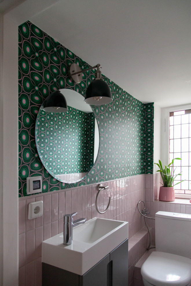 Example of a small eclectic master pink tile and ceramic tile ceramic tile, pink floor, single-sink and wallpaper toilet room design in Berlin with flat-panel cabinets, gray cabinets, a one-piece toilet, green walls, an integrated sink, laminate countertops, white countertops and a floating vanity