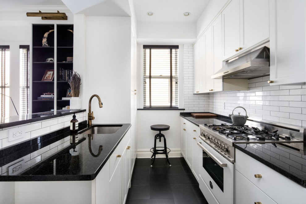 Example of a mid-sized transitional galley ceramic tile and black floor eat-in kitchen design in New York with a single-bowl sink, shaker cabinets, white cabinets, granite countertops, white backsplash, ceramic backsplash, white appliances, black countertops and no island