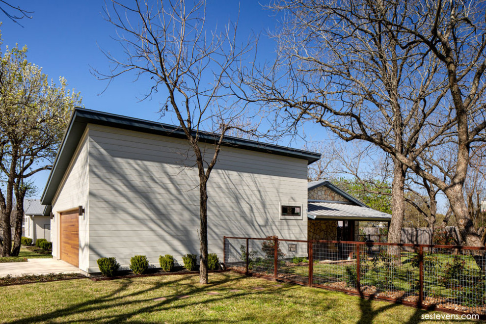 Modelo de fachada de casa beige y gris actual de tamaño medio de una planta con revestimientos combinados, tejado a dos aguas, tejado de metal y tablilla