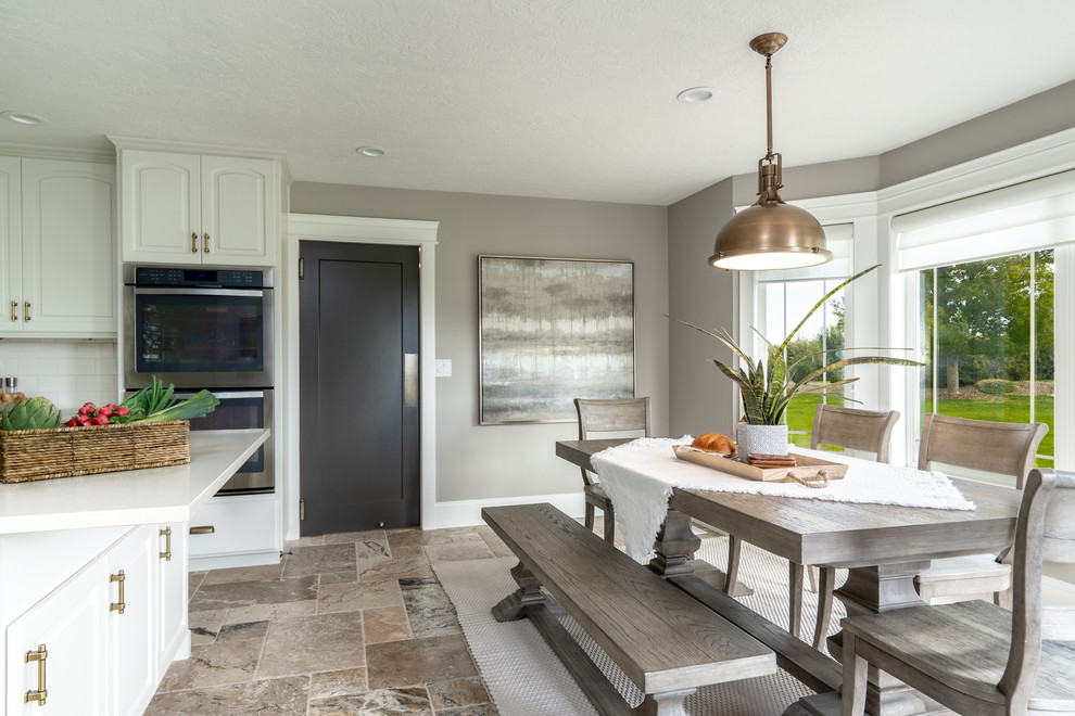 Example of a transitional u-shaped travertine floor and brown floor open concept kitchen design in Seattle with an undermount sink, raised-panel cabinets, white cabinets, quartz countertops, white backsplash, porcelain backsplash, stainless steel appliances, an island and white countertops