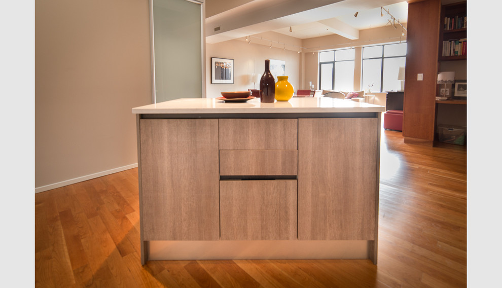 Photo of a mid-sized contemporary l-shaped eat-in kitchen in Boston with a drop-in sink, flat-panel cabinets, white cabinets, solid surface benchtops, beige splashback, glass sheet splashback, stainless steel appliances and medium hardwood floors.