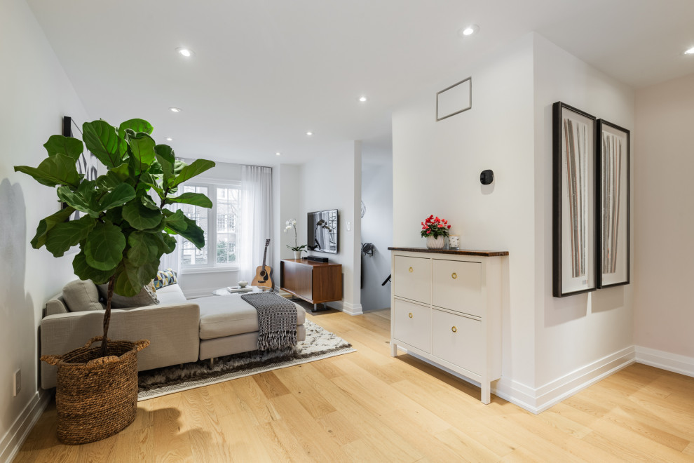 Modelo de salón con rincón musical abierto minimalista de tamaño medio con paredes blancas, suelo de madera en tonos medios y televisor colgado en la pared