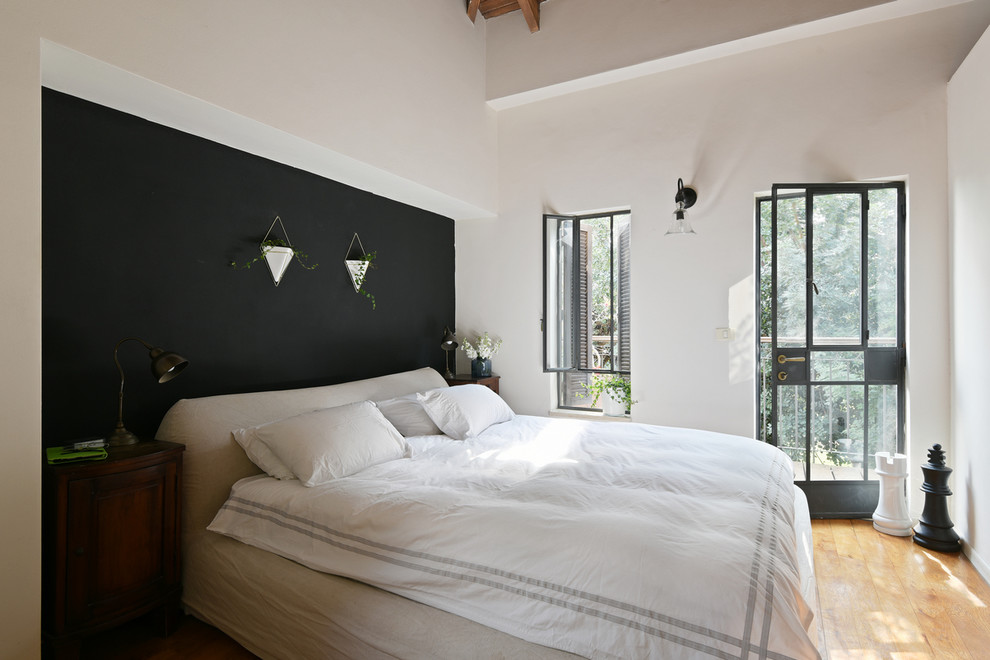 Photo of a scandinavian bedroom in Tel Aviv with black walls and light hardwood floors.