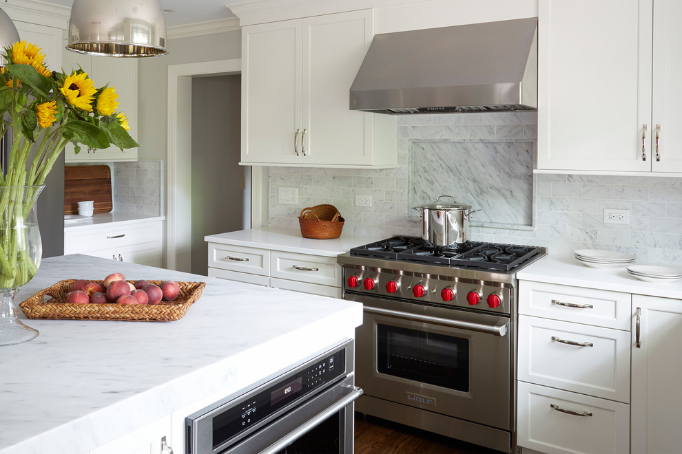 Mid-sized transitional u-shaped medium tone wood floor eat-in kitchen photo in Chicago with shaker cabinets, white cabinets, marble countertops, white backsplash, porcelain backsplash, stainless steel appliances, an island and a single-bowl sink