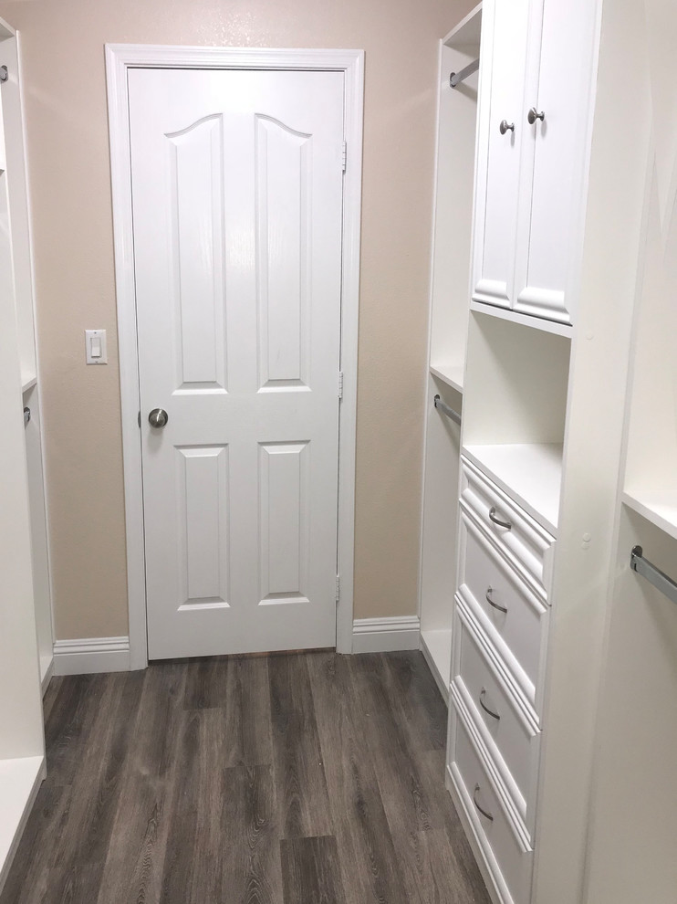 This is an example of a small traditional gender-neutral walk-in wardrobe in Las Vegas with shaker cabinets, white cabinets, vinyl floors and brown floor.