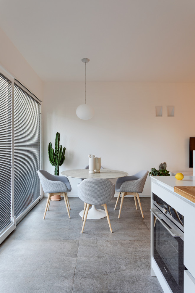 This is an example of a contemporary dining room in Bologna with white walls, porcelain floors and grey floor.