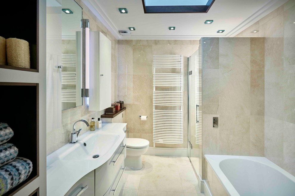 This is an example of a contemporary bathroom in London with flat-panel cabinets, white cabinets, a drop-in tub, an open shower, beige tile, stone tile, beige walls, marble floors, an integrated sink and glass benchtops.