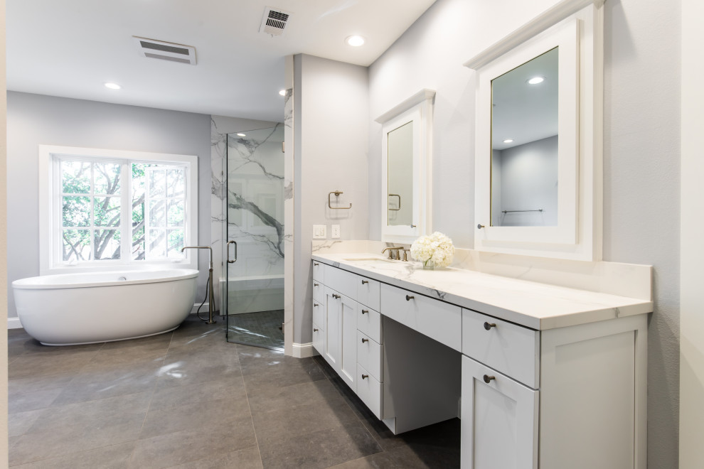 Inspiration for a mid-sized contemporary master bathroom in Dallas with white cabinets, a freestanding tub, an open shower, a one-piece toilet, white tile, stone slab, grey walls, an undermount sink, granite benchtops, grey floor, an open shower, white benchtops, an enclosed toilet and a double vanity.