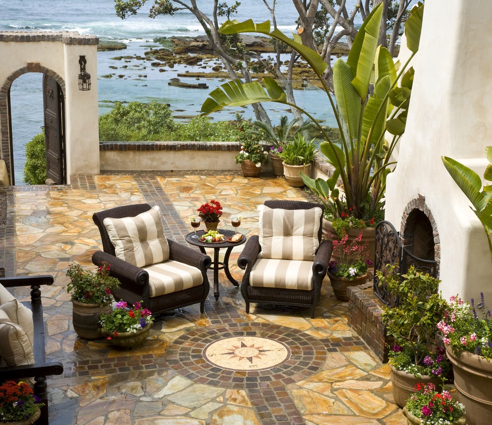 Photo of a mediterranean side yard patio in San Diego with natural stone pavers, a fire feature and no cover.