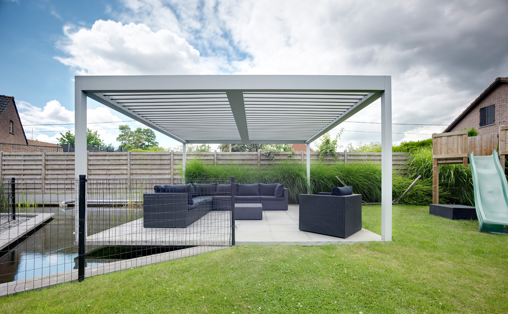 This is an example of a contemporary backyard patio in Buckinghamshire with concrete pavers and a pergola.