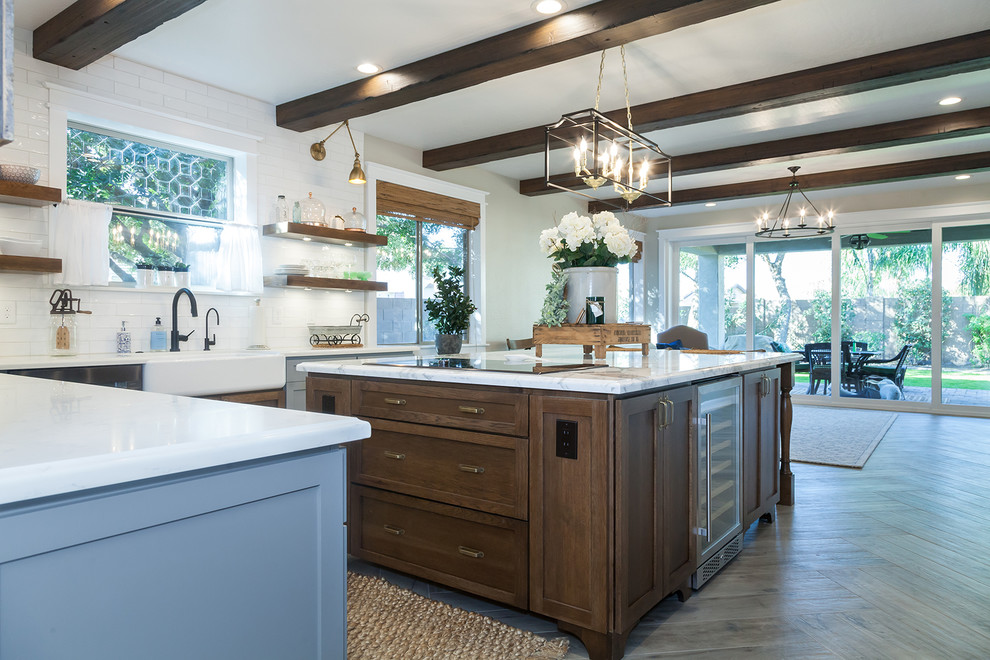 Eat-in kitchen - large transitional l-shaped porcelain tile and brown floor eat-in kitchen idea in Phoenix with a farmhouse sink, shaker cabinets, gray cabinets, quartz countertops, white backsplash, glass sheet backsplash, stainless steel appliances, an island and white countertops