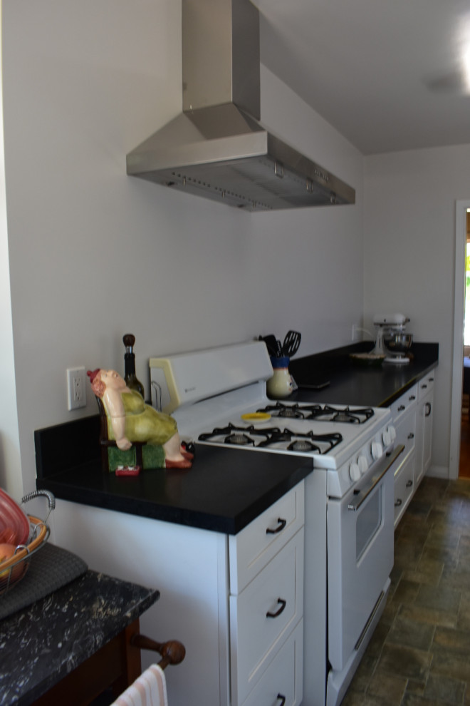 Medium sized contemporary galley kitchen/diner in Los Angeles with a single-bowl sink, shaker cabinets, white cabinets, composite countertops, black splashback, engineered quartz splashback, stainless steel appliances, ceramic flooring, no island, multi-coloured floors and black worktops.