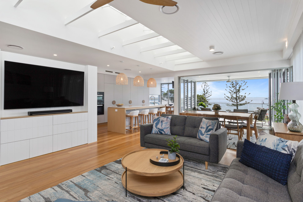 Design ideas for a large beach style open concept living room in Brisbane with white walls, medium hardwood floors, a built-in media wall, brown floor and exposed beam.