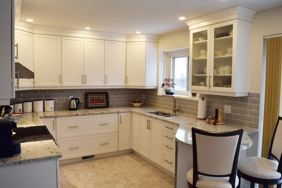 Enclosed kitchen - mid-sized transitional u-shaped ceramic tile enclosed kitchen idea in Ottawa with an undermount sink, shaker cabinets, white cabinets, granite countertops, gray backsplash, glass tile backsplash, stainless steel appliances and a peninsula