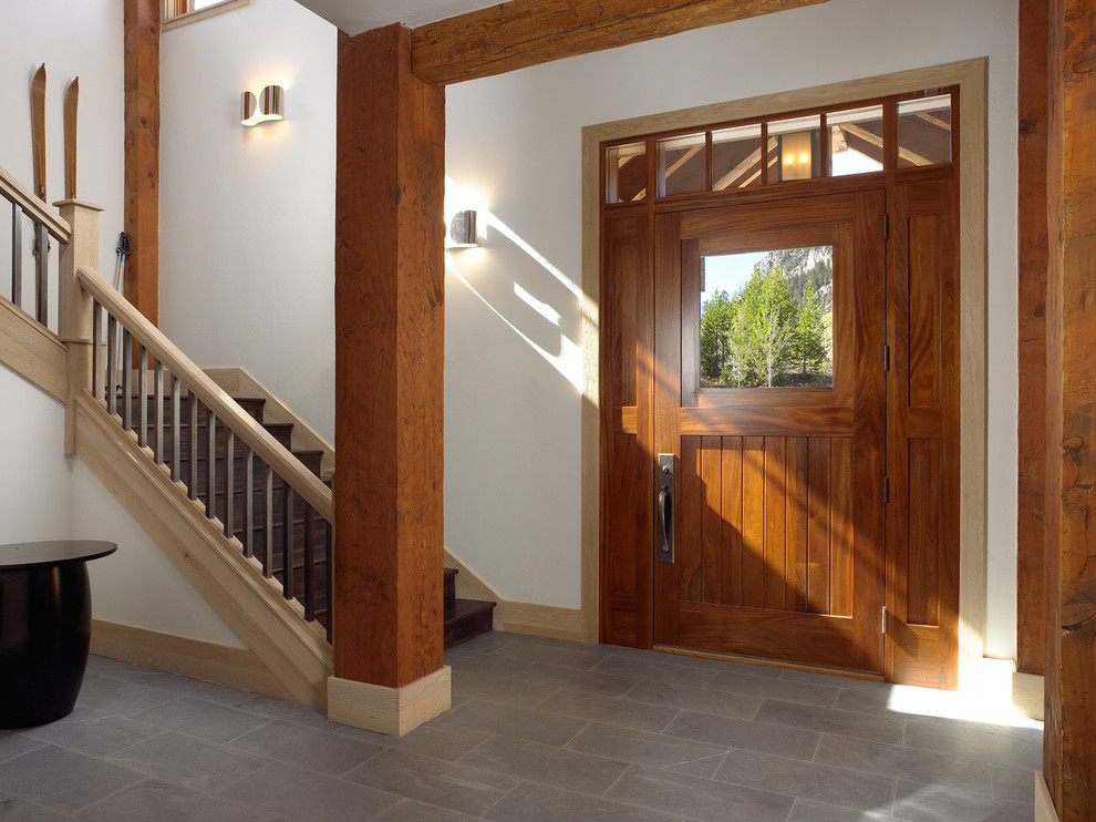 This is an example of a large country front door in Other with white walls, a single front door, a medium wood front door, ceramic floors and grey floor.