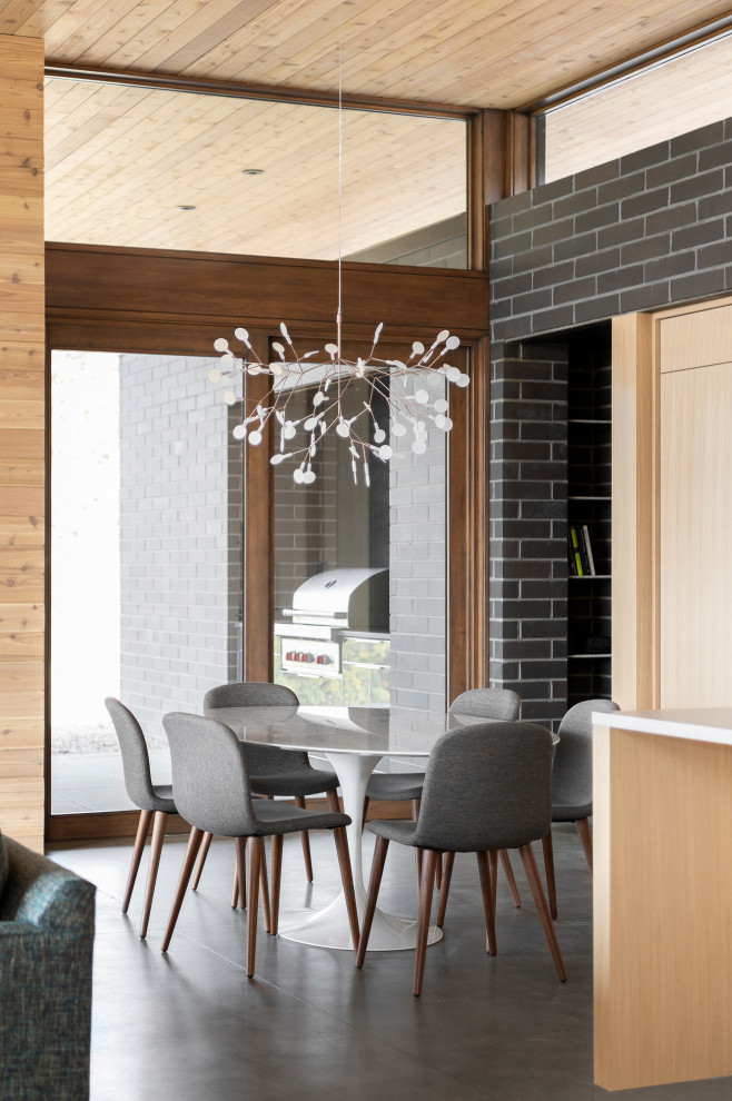 Idee per una sala da pranzo aperta verso il soggiorno minimalista con pavimento in cemento, pavimento grigio, soffitto in legno, pareti in mattoni e pareti nere