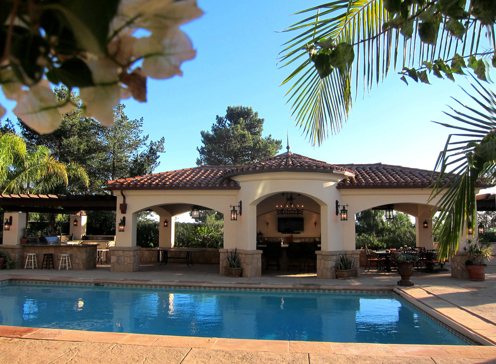 This is an example of a mid-sized mediterranean backyard rectangular pool in Santa Barbara with a pool house and stamped concrete.