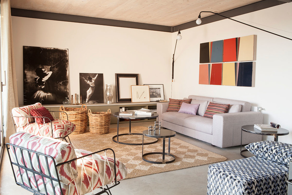 Photo of an eclectic living room in Barcelona with white walls, concrete floors and grey floor.