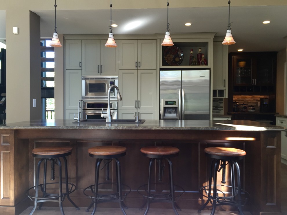 Example of a mid-sized transitional l-shaped light wood floor and gray floor eat-in kitchen design with a double-bowl sink, shaker cabinets, white cabinets, multicolored backsplash, matchstick tile backsplash, stainless steel appliances and an island