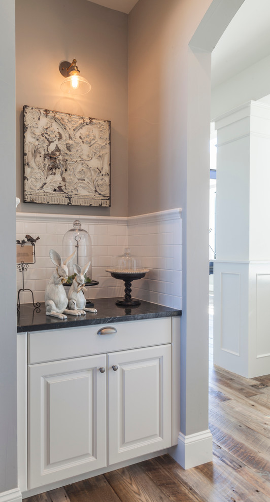 Transitional medium tone wood floor kitchen photo in Denver with raised-panel cabinets, white cabinets, soapstone countertops, white backsplash, subway tile backsplash and an island