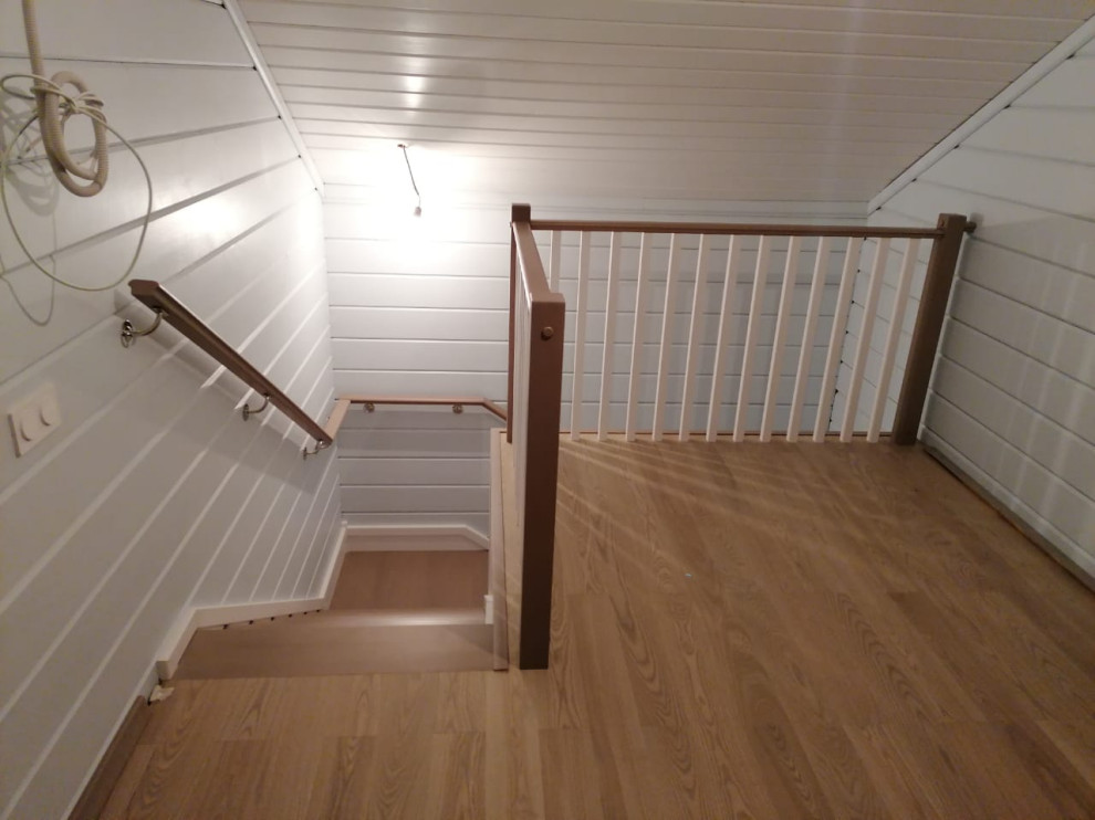 This is an example of a small traditional wood l-shaped staircase in Moscow with wood risers, wood railing and planked wall panelling.