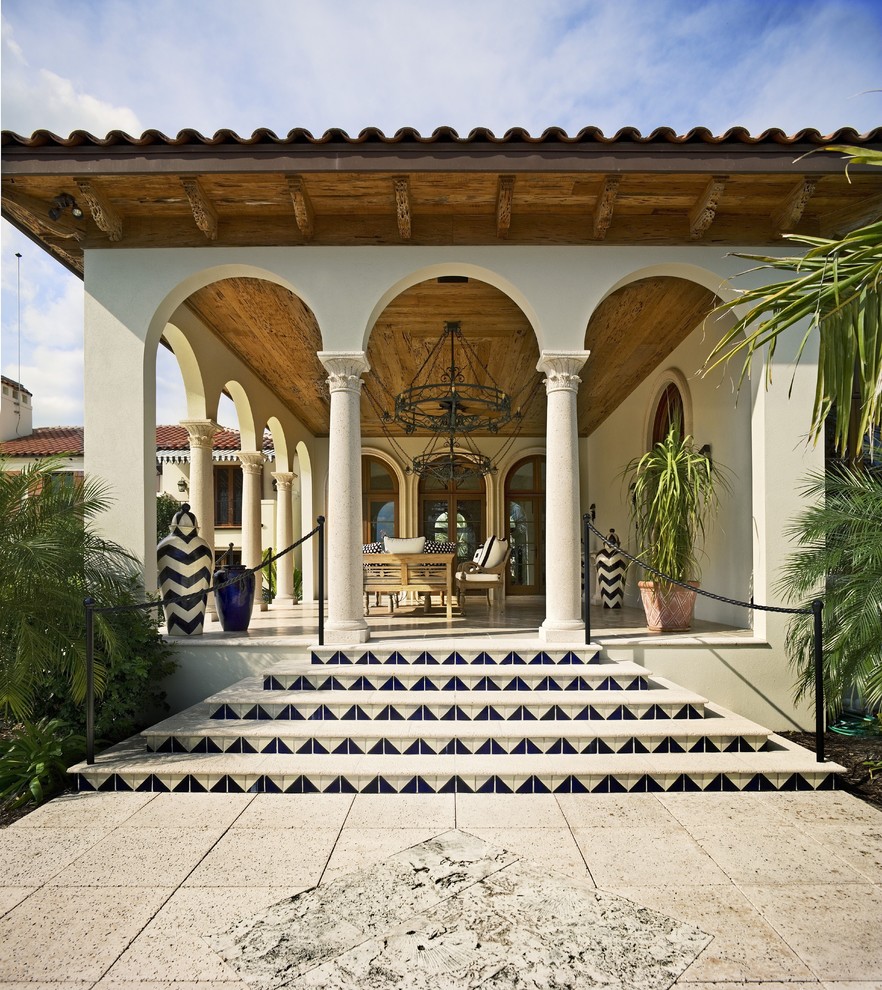 Inspiration for a large mediterranean backyard patio in Tampa with a water feature, a roof extension and tile.