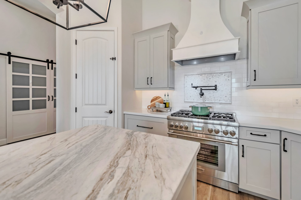 Kitchen - large transitional u-shaped porcelain tile, brown floor and exposed beam kitchen idea in Phoenix with a farmhouse sink, shaker cabinets, gray cabinets, quartzite countertops, white backsplash, porcelain backsplash, stainless steel appliances, an island and white countertops