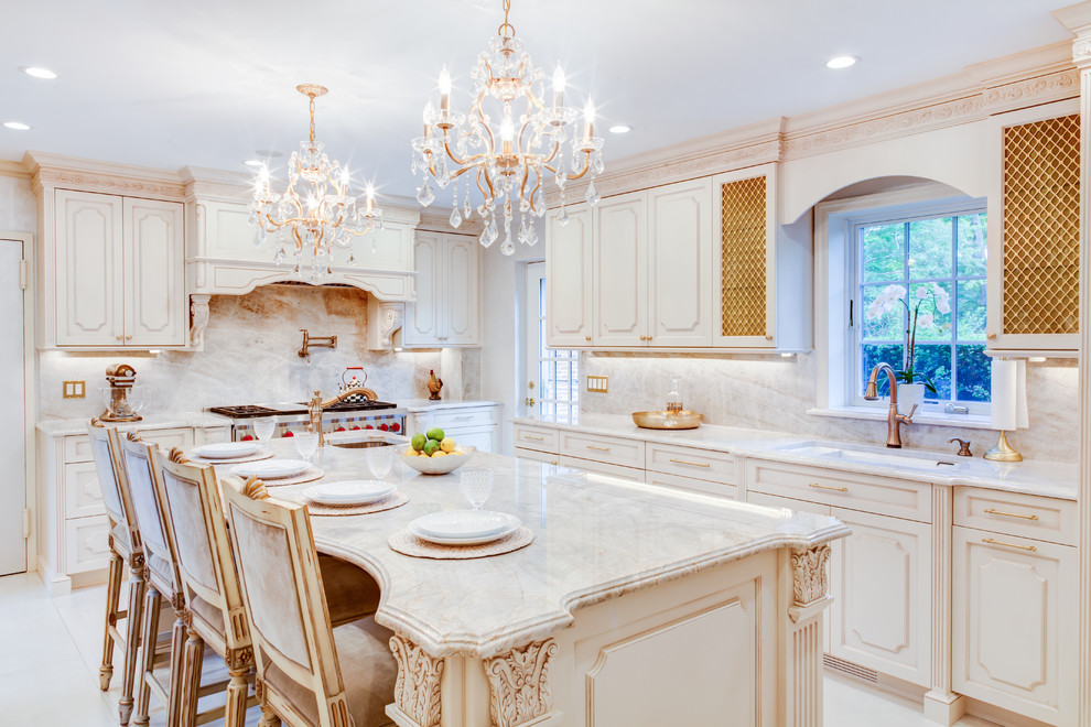 Design ideas for a mid-sized traditional separate kitchen in New York with raised-panel cabinets, beige cabinets, beige splashback, stone slab splashback, panelled appliances, ceramic floors, with island, white floor, an undermount sink and marble benchtops.