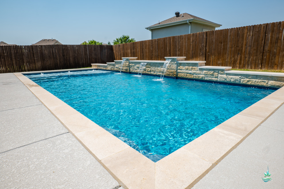 Diseño de piscina alargada de estilo americano de tamaño medio rectangular en patio trasero con paisajismo de piscina y losas de hormigón