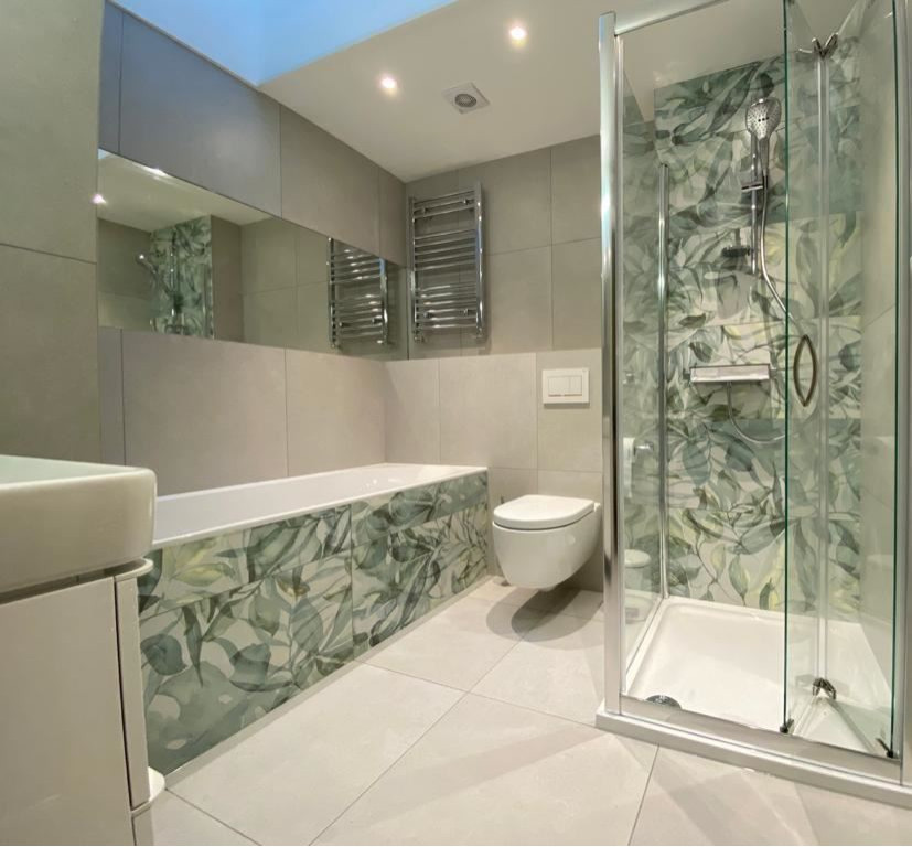 Design ideas for a mid-sized contemporary master bathroom in West Midlands with a drop-in tub, a corner shower, a wall-mount toilet, multi-coloured tile, porcelain tile, multi-coloured walls, porcelain floors, grey floor, a hinged shower door, a single vanity and a floating vanity.