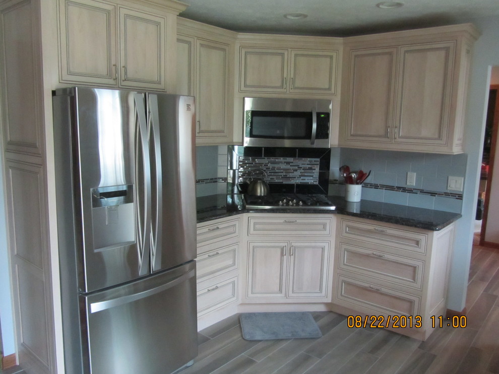 Example of a transitional u-shaped eat-in kitchen design in Cleveland with a farmhouse sink, distressed cabinets, granite countertops and stainless steel appliances