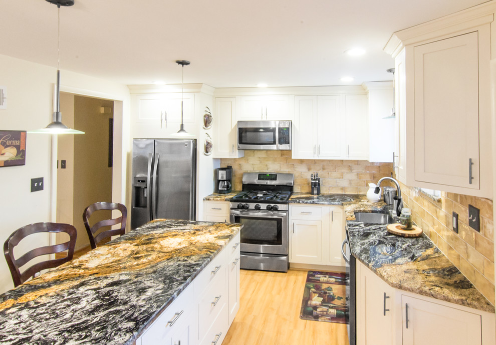 This is an example of a mid-sized mediterranean l-shaped eat-in kitchen in Philadelphia with an undermount sink, shaker cabinets, white cabinets, granite benchtops, beige splashback, ceramic splashback, stainless steel appliances, with island and multi-coloured benchtop.