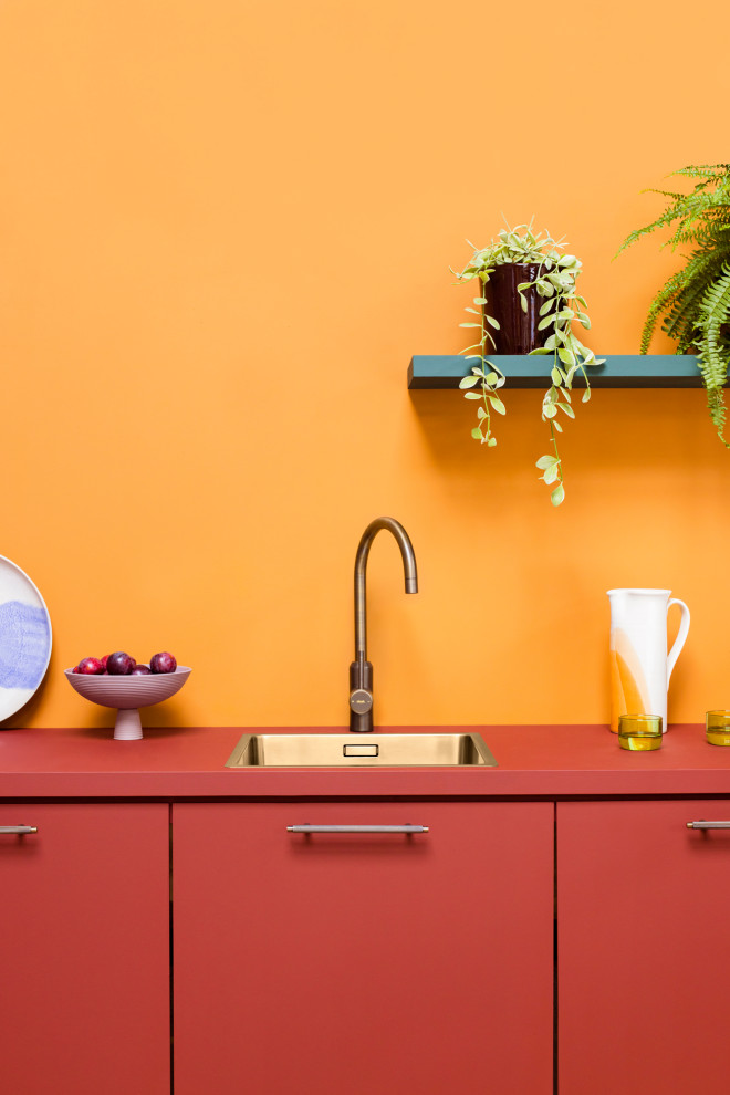 Modern inredning av ett litet röd linjärt rött kök med öppen planlösning, med en enkel diskho, släta luckor, röda skåp, träbänkskiva, orange stänkskydd och stänkskydd i trä