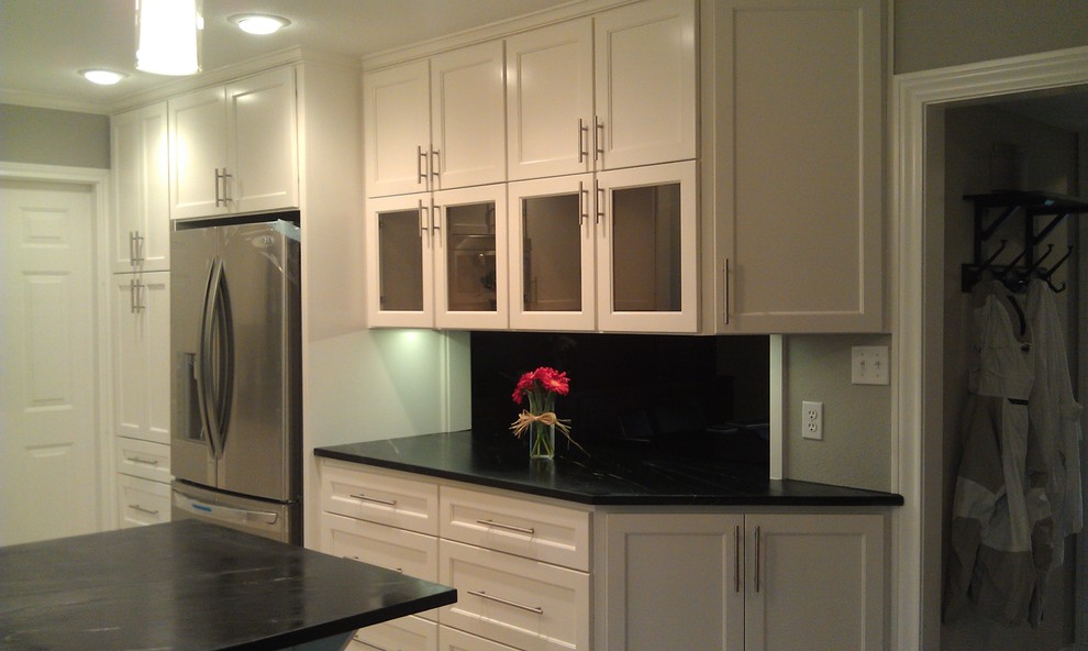 Inspiration for a large transitional l-shaped light wood floor open concept kitchen remodel in Austin with an undermount sink, shaker cabinets, white cabinets, granite countertops, glass sheet backsplash, stainless steel appliances and an island