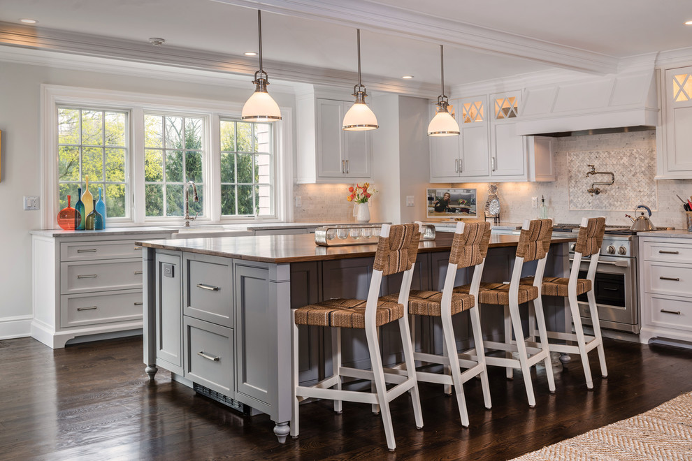 Traditional kitchen in New York with a farmhouse sink, shaker cabinets, white cabinets, multi-coloured splashback, stainless steel appliances, dark hardwood floors, with island and brown floor.