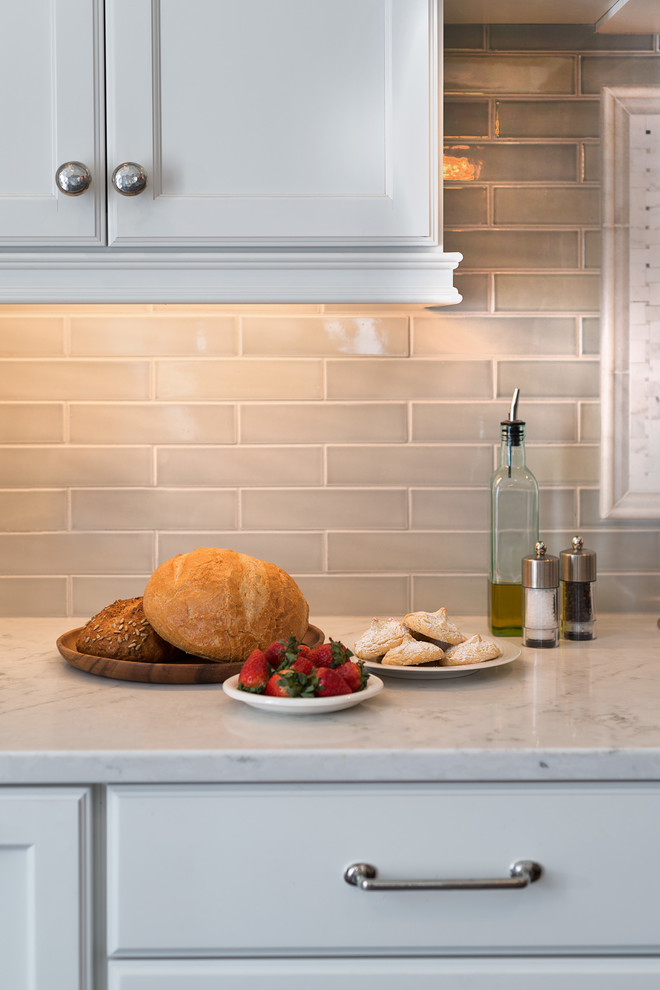 Example of a huge transitional l-shaped medium tone wood floor home design design with flat-panel cabinets, white cabinets, marble countertops, gray backsplash, porcelain backsplash, paneled appliances and an island