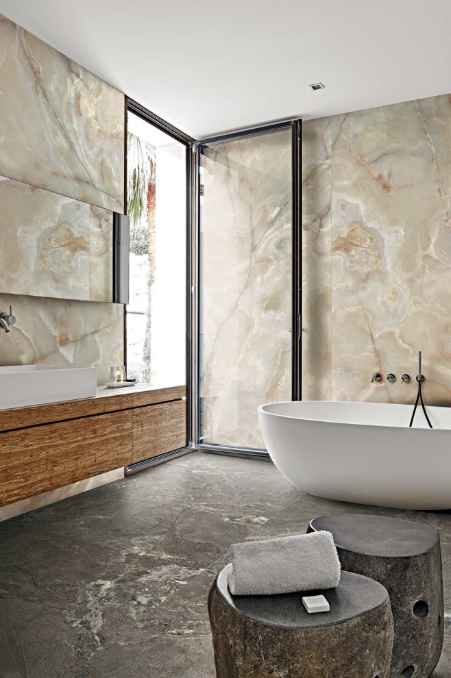 Photo of a large contemporary master bathroom in Other with ceramic floors, flat-panel cabinets, medium wood cabinets, a freestanding tub, beige tile, a vessel sink, grey floor and brown benchtops.