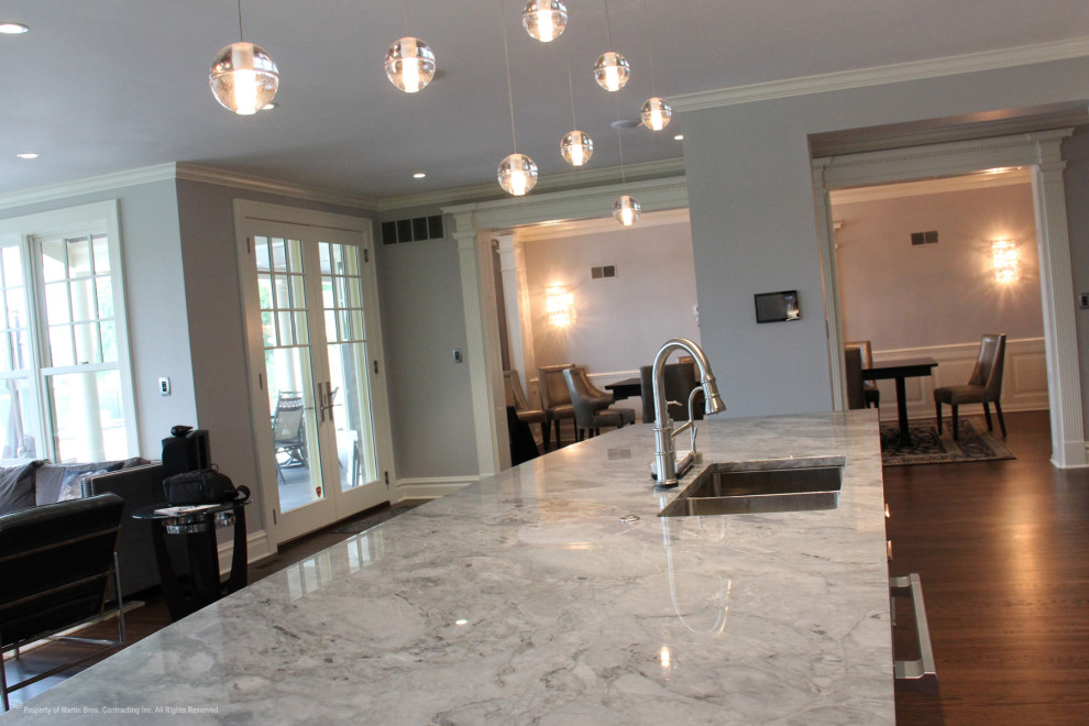 Inspiration for a large transitional single-wall medium tone wood floor open concept kitchen remodel with a double-bowl sink, recessed-panel cabinets, gray cabinets, marble countertops, multicolored backsplash, stainless steel appliances, an island and marble backsplash