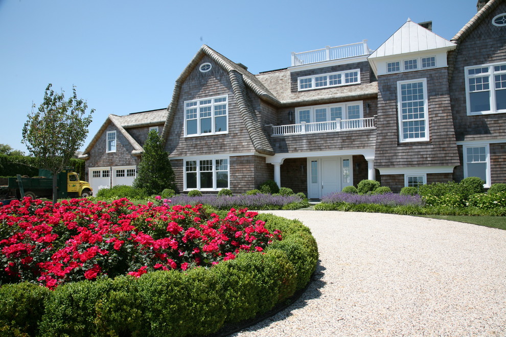 Photo of a large beach style two-storey brown house exterior in New York with wood siding, a gambrel roof and a shingle roof.