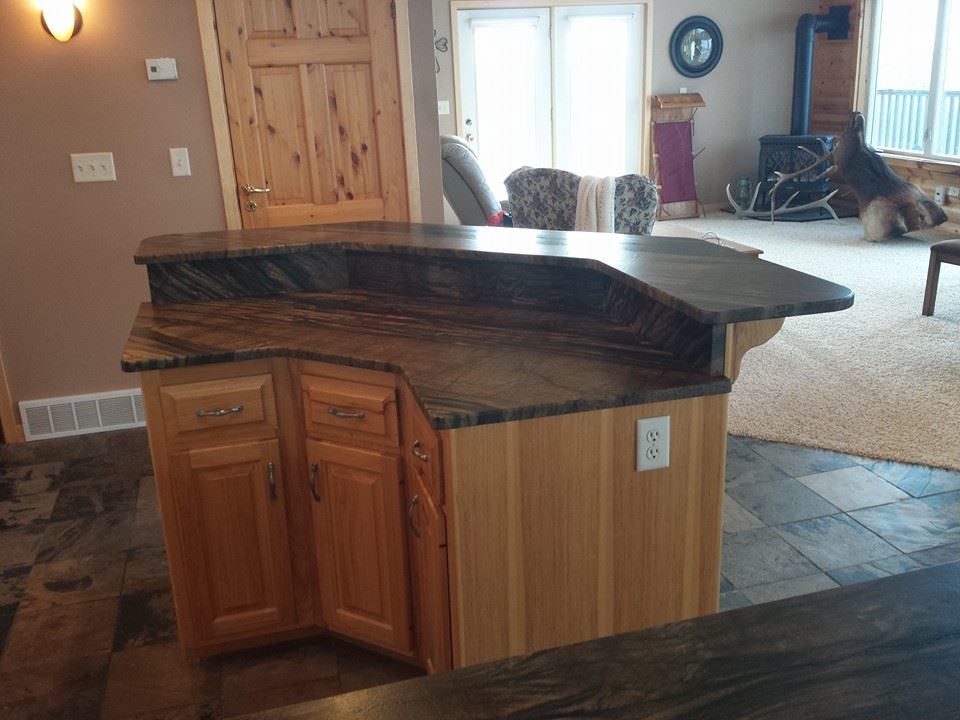 Mid-sized mountain style l-shaped slate floor eat-in kitchen photo with raised-panel cabinets, light wood cabinets, quartzite countertops, stone slab backsplash and an island