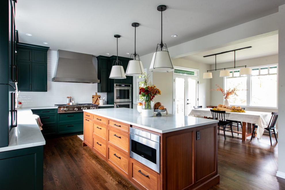 Design ideas for a mid-sized transitional l-shaped eat-in kitchen in Seattle with a farmhouse sink, shaker cabinets, green cabinets, white splashback, subway tile splashback, panelled appliances, dark hardwood floors, with island, brown floor, green benchtop and quartz benchtops.