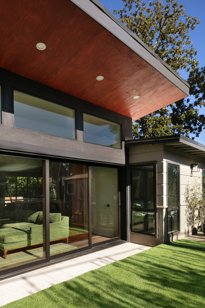 Idées déco pour une façade de maison verte rétro en bois et planches et couvre-joints de taille moyenne et de plain-pied avec un toit plat et un toit blanc.