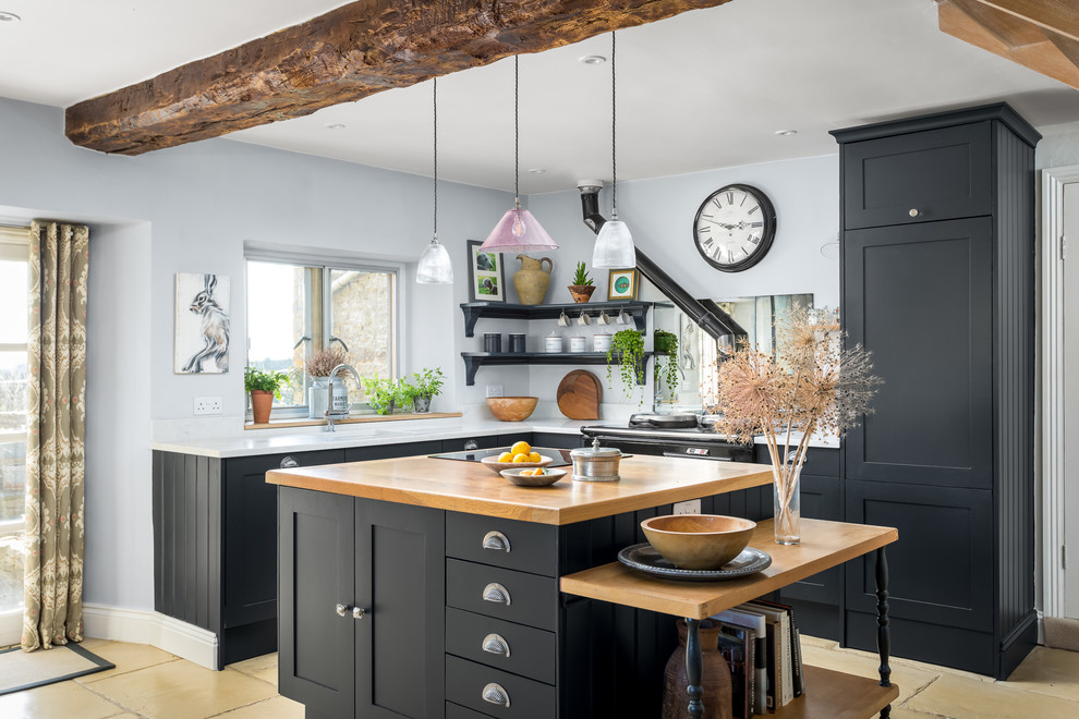 This is an example of a country u-shaped kitchen in Gloucestershire with shaker cabinets, black cabinets, with island, beige floor and white benchtop.