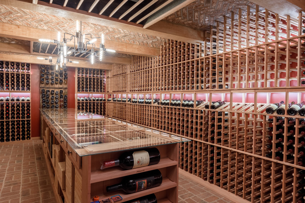 This is an example of a large traditional wine cellar in Other with storage racks, brick floors and red floor.