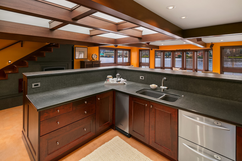 Design ideas for a large contemporary u-shaped open plan kitchen in Seattle with a double-bowl sink, shaker cabinets, dark wood cabinets, granite benchtops, black splashback, stone slab splashback, stainless steel appliances, concrete floors, a peninsula, brown floor and black benchtop.