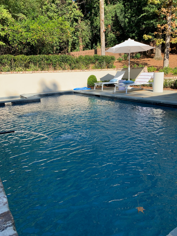 Imagen de piscina tradicional de tamaño medio rectangular en patio trasero con adoquines de piedra natural y paisajismo de piscina